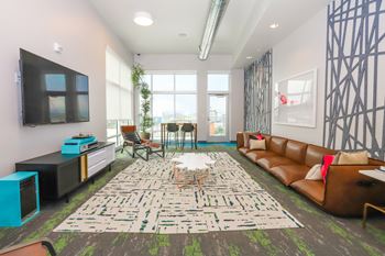A living room with a large rug and a brown couch.